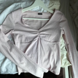 Rosa långärmad topp från Gina Tricot - Säljer en söt rosa långärmad topp från Gina Tricot med rynkdetalj vid bysten och en v-ringad hals. Nytt skick i storlek Xs men passar även S. Pris kan diskuteras, kom privat för fler bilder💕