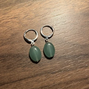 Silverörhängen med gröna stenar - Snygga silverörhängen med ovala gröna stenar som hänger elegant. Perfekta för att ge en touch av färg till din outfit. Lätta att bära och passar till många tillfällen.