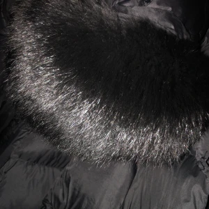 Svart dunjacka med pälsdetalj - Snygg svart dunjacka med en lyxig pälsdetalj runt kragen. Jackan har en bälte i midjan för en figursydd look och är perfekt för kalla dagar. Den är långärmad och har en stilren design, äkta päls