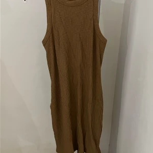 Brun ribbad klänning från Gina Tricot - Säljer en stilren brun ribbad klänning från Gina Tricot. Klänningen är ärmlös och har en enkel design som passar perfekt för både vardag och avslappnade tillfällen. Den är gjord i ett mjukt material som ger en bekväm passform.