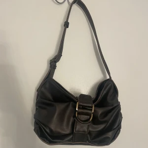 Brun axelväska  - Snygg brun axelväska från Zara med justerbar axelrem och dekorativt bälte på framsidan. Stängs med magnetknapp och dragkedja