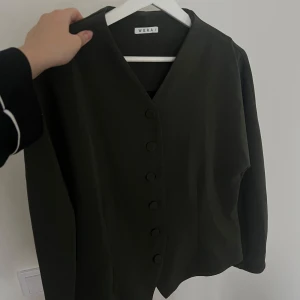 Mörkgrön kofta - Säljer denna mörkgröna koftan från Wera. Sitter figurnära kroppen och har knappar i mitten. Inga defekter förekommer💚