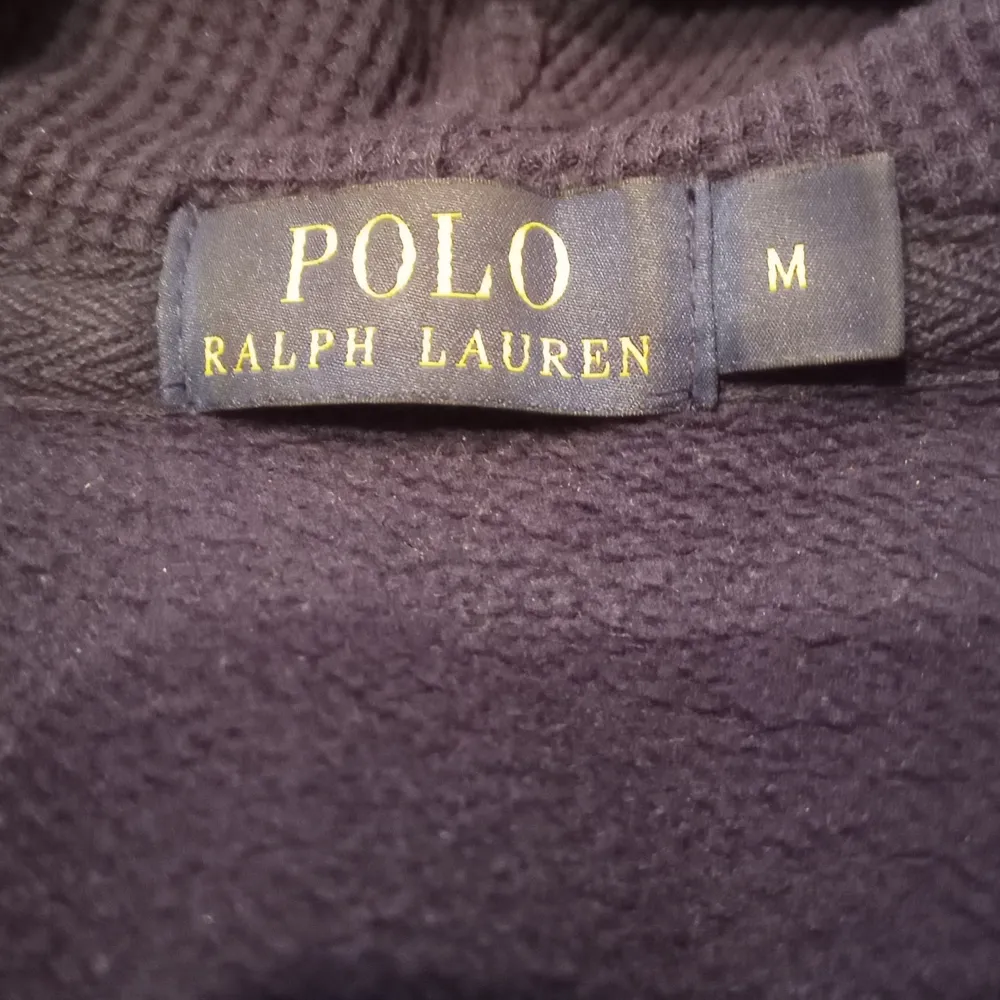 Säljer en snygg mörkblå hoodie från Ralph Lauren med dragkedja och det klassiska gula logotypen på bröstet. Perfekt för höst och vår, med långa ärmar och en skön huva. Passar både till vardags och chilliga dagar. 🧢. Tröjor & Koftor.