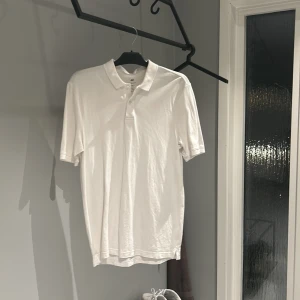 Vit pikétröja från H&M - Säljer en klassisk vit pikétröja från H&M i storlek S. Tröjan har en normal passform och är tillverkad i mjuk bomull. Perfekt för både vardag och lite mer uppklädda tillfällen. Den har korta ärmar och en stilren krage med knappar. Passar perfekt till jeans eller chinos!