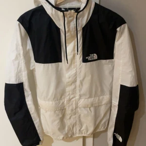 The North face jacka  - Säljer en snygg vit och svart vindjacka från The North Face. Jackan är sparsamt använd och går inte att få tag i längre någonstans. Skick 8/10 storlek S