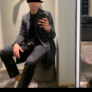 Kashmirrock från SAND Copenhagen - En gråsvart kashmirrock från SAND Copenhagen i storlek 48/M. Inhandlad från NK i Stockholm. Superfinkvalitet och endast använd en vinter. Kan användas som höst- och vinterrock. Säljs pga för liten i storleken för mig. Jag använder storlek 52/L numera. NYPRIS: 4.999