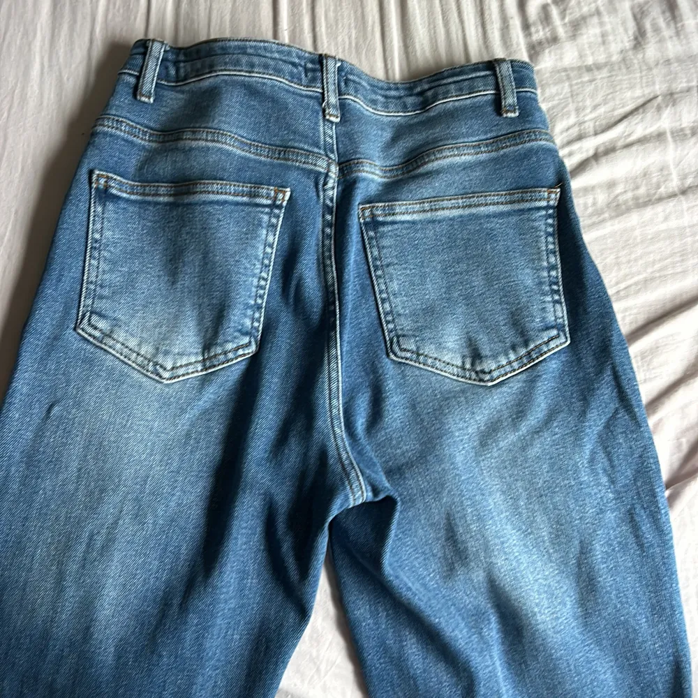 Säljer ett par snygga blå jeans från H&M i storlek 36.  De har en klassisk femficksdesign och coola slitna detaljer på knäna. Perfekta för en avslappnad vardagslook! 🕶️. Jeans & Byxor.