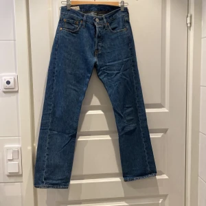 Levi's 501 Jeans - Säljer ett par klassiska Levi's 501 jeans i blå denim. De har en straight passform och är i nyskick. Perfekta för både vardag och fest!