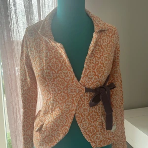 Odd Molly kofta - Odd Molly kofta i en hostig orange färg med vitt mönster, ett lila snöre att knyta under bysten. Koftan är i storlek 0 vilket innebär XS/S