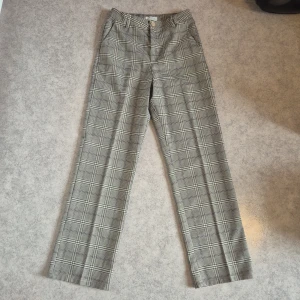 Rutiga kostymbyxor  - Fina rutiga kostymbyxor med rosa inslag, använda men i bra skick, justerbar midja