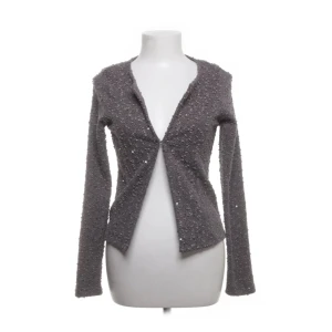 Grå glittrig kofta - Snygg grå kofta med glittrande detaljer. Den har en öppen design och långa ärmar, perfekt för att lägga till lite glamour till din outfit. Passar bra till både vardag och festliga tillfällen.