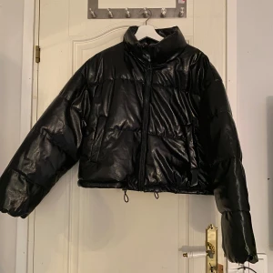 Svart glansig pufferjacka från H&M - Säljer en svart glansig pufferjacka från H&M Jackan har en hög krage och dragkedja framtill. Helt ny, aldrig använd, säljer pga ej passade mig. Prislappen kvar. Nypris 399kr, mitt pris 250kr