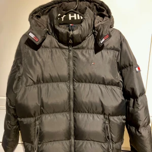 Dunjacka från Tommy Hilfiger strl 176 - Mörkblå dunjacka från Tommy Hilfiger i strl 176. Sparsamt använd och mkt fint skick.