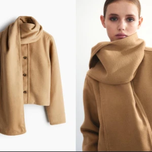 Beige kappa med knappar från H&M - Snygg beige kappa med knappar och en matchande halsduk. Den har en rund halsringning och långa ärmar, perfekt för kyligare dagar. Stilren och enkel design som passar till mycket.                                                                           Storlek: L (44-46), helt ny och oanvänd. 