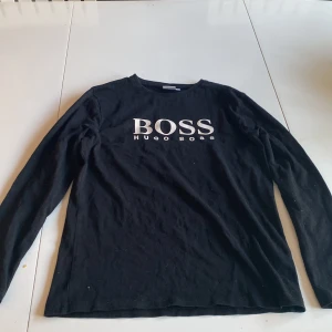 Svart långärmad tröja från Hugo Boss  - Säljer en stilren svart långärmad tröja från Hugo Boss den är använd några få gånger men blev snabbt för lite är i perfekt skick. Pris kan diskuteras.