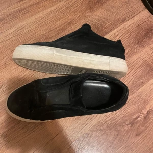 Svarta sneakers från Arigato - Snygga svarta sneakers från Axel Arigato. Skorna är i bra skick, 8/10, däremot börjar den väldigt lilla guldiga arigato texten försvinna från sidan av skon (bild 4). Detta syns däremot inte vid användning. Har ej tvättat skorna men detta går snabbt att göra. Låda medföljer. Hör av er vid frågor!
