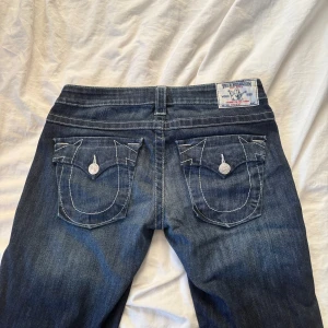 Lågmidjade jeans från True Religion - Säljer nu dessa sååå coola jeans då de tyvärr inte passar mig längre. Kan därför inte skicka med bilder på tyvärr, men kan hänvisa till måtten nedan. Storleken är 29 vilket enligt true religions hemsida stämmer överens med en storlek medium. lnnerbenslängd: 77 cm Grenhöjd: 20 cm Ben längst ner: 21 cm Lårbredd: ca 25 cm Midjemått rakt över: 38 cm Höft: ca 45 cm rakt över 
