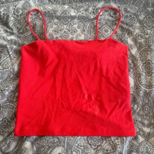 Röd linne från Gina Tricot - Säljer en snygg röd linnetopp från Gina Tricot. Toppen har smala axelband och är perfekt för varma dagar. Enkel och stilren design som passar till mycket. Aldrig använd, Hör av dig vid intresse! ❤️