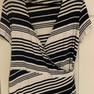 Egensydd Randig omlottklänning - Snygg randig omlottklänning i marinblått och vitt. Klänningen har korta ärmar och ett omlottmönster. Perfekt för sommaren 🌸 skulle säga att den är L i storlek