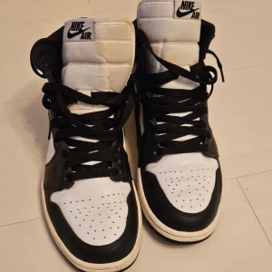 Nike Air Jordans i svart och vitt stl 41(små i storlek) - Snygga Nike Air Jordans i klassisk svart och vit färgkombination. Skorna har hög snörning och en ikonisk design med Nike-loggan på sidan. Perfekta för en stilren look. Skorna är storlek 41 men är små i storlek. Snarare storlek 40 än 41