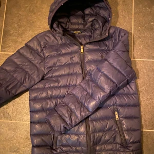 Blå dunjacka från Ralph Lauren - Snygg blå dunjacka från Ralph Lauren. Perfekt till kalla sommarkvällar och till våren! Nypris 1900. Hör av er vid intresse eller frågor!