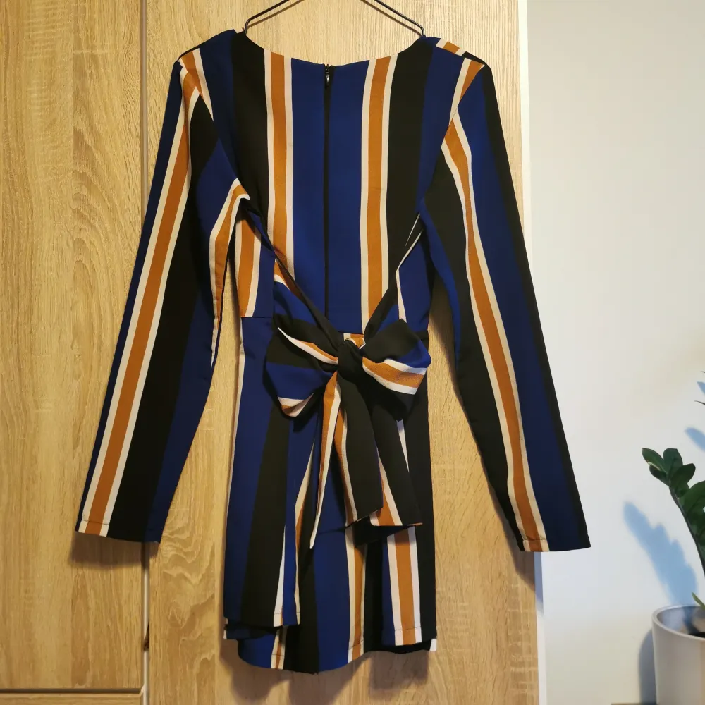 Snygg långärmad randig playsuit / jumpsuit / byxdress från In The Style i blått, svart, vitt och brunt/senapsbrun. Dragkedja i ryggen och knyts bak. 🥰. Mekot.