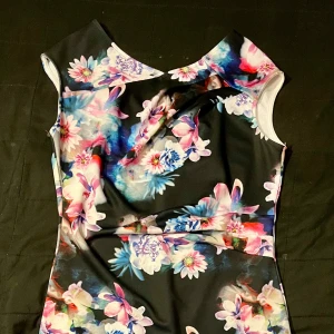 Blommig klänning från Lipsy - Säljer en färgglad blommig klänning från Lipsy. Klänningen har ett vackert mönster i rosa, blått och vitt på en svart bakgrund. Perfekt för att sticka ut med sin unika design.