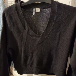 Svart V-ringad tröja från Divided - Säljer en stilren svart V-ringad tröja från Divided. Tröjan har långa ärmar och ribbade kanter vid ärmslut och nederkant. Perfekt för en enkel och snygg look. Den kommer inte till användning💗ni kan fråga om bild på💕