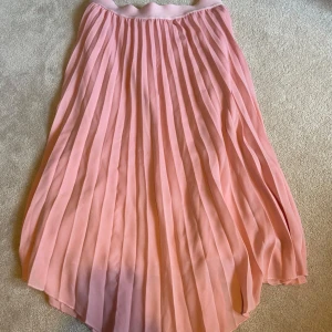 Rosa plisserad kjol från Saint Tropez - Säljer en söt rosa plisserad kjol från Saint Tropez. Kjolen har en elastisk midja för bekväm passform och ett luftigt fall. Perfekt för en somrig look 💞