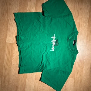 Grön t-shirt med tryck - Snygg grön t-shirt med ett coolt vitt tryck på framsidan. Perfekt för en avslappnad stil. T-shirten har en normal passform och korta ärmar.