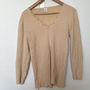 Säljer en beige långärmad tröja med spets, det står ingen storlek men skulle säga passar S/M - Bra skick, inte använd.