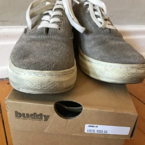 Buddy Dachshund sneakers, mocka, made in Japan - Sneakers i mocka från japanska Buddy. Modellen är en Dachshund-variant, heter ”Dachs low”. Grå, lätt sandfärgade. Köpta på Caliroots för ca 8-9 år sen. Använda en del men fortfarande gott skick. Nypris en bit över 1000 kr. Storlek JP26,5 / US8,5