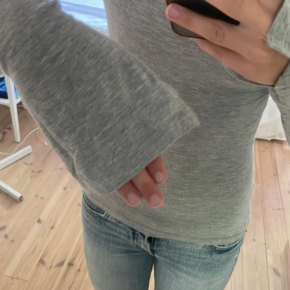 Säljer en grå långärmad tröja i storlek XS. Tröjan är tight och har en rund halsringning. Den är gjord av ett mjukt och stretchigt material, perfekt för vardagsbruk. Passar bra till jeans eller kjol. Skicket är bra, knappt använd.. Toppar.