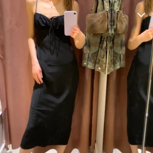 Satinklänning - Svart satinklänning från Gina Tricot med knytning upptill. Sååå fin till fest, studentskivor mm. Använd endast en gång på min egen studentskiva. Med stickad tröja över ser det ut som en sån fin kjol. Otrolig passform oxå!