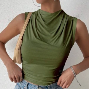Grön ärmlös topp - Säljer en snygg grön ärmlös topp som är perfekt för sommaren. Toppen har en draperad hals och är tillverkad i ett mjukt och stretchigt material som sitter tight på kroppen. Den är enkel men stilren och kan lätt matchas med både jeans och kjolar. Perfekt för både vardag och fest!