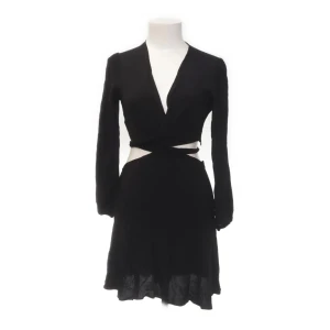 Zara klänning - Trendig svart omlottklänning med långärmad design och öppen rygg. Klänningen har en knytning i midjan som ger en snygg siluett. Perfekt för en kväll ute eller en speciell tillställning. Klänningen är från Zara i stl m❤️