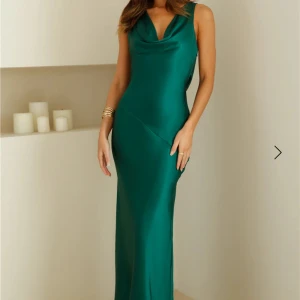 Grön långklänning med öppen rygg - Elegant grön långklänning i satin med en vacker draperad halsringning och öppen rygg. Klänningen har en tajt passform runt midja vilket ger en hourglass figur, knytband i ryggen för extra detalj. Det är köpt på hello Molly i storlek S för 1750kr. Den är aldrig använt och har prislappen kvar, skriv för fler bilder. 