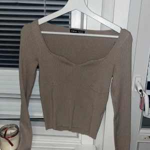 Beige ribbad tröja från Shein - Säljer en stilren beige ribbad tröja från Shein. Tröjan har en unik design med en subtil v-ringning och långa ärmar. Perfekt för en chic och bekväm look. Passar bra till både jeans och kjol.