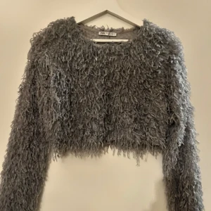 Blå fluffig tröja från Zara - Säljer en supermjuk och fluffig grå tröja från Zara. Den är croppad och har långa ärmar. Tröjan unik stil med sin textur. 