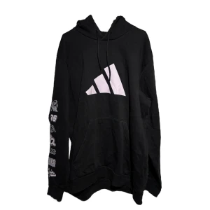 Svart hoodie från Adidas - Säljer en svart hoodie från Adidas med stor vit logga på framsidan. Hoodien har en tryck på ärmen.