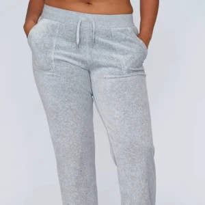Grå mjukisbyxor med snörning från juicy couture - Snygga och bekväma grå mjukisbyxor med snörning i midjan. Perfekta för en avslappnad stil. Byxorna har en loose passform och praktiska fickor framtill.
