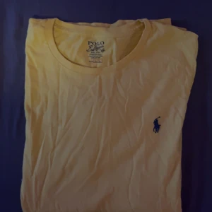Gul t-shirt från Polo Ralph Lauren - Säljer en gul t-shirt från Polo Ralph Lauren med den klassiska broderade loggan i blått på bröstet. T-shirten är tillverkad i 100% bomull och har en normal passform. Perfekt för en avslappnad stil.( L) fast i slim fit så skulle säga den passar(  M )