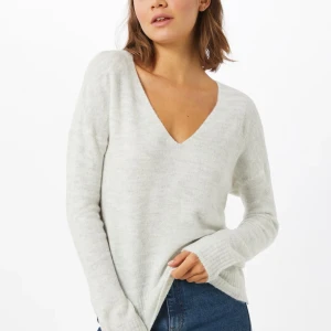 ljusgrå stickad tröja med v-ringning - Säljer en mysig ljusgrå stickad tröja med v-ringning. Tröjan har långa ärmar och en avslappnad passform, perfekt för kyligare dagar. Den är enkel att matcha med jeans eller kjol för en stilren look.