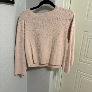Rosa tröja med pärlor från Zara - Säljer en söt rosa tröja från Zara dekorerad med pärlor över hela ytan. Tröjan har långa ärmar och en rund halsringning. 🌸