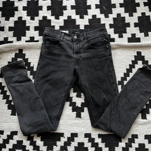 Replay jeans - Snygga svarta jeansbyxor med en klassisk femficksdesign. De har en knapp och dragkedja framtill och är perfekta för en stilren look. Passformen är tight och de är tillverkade i ett stretchigt material för extra komfort. Skick 9/10. ||| storlek w27-28 och L30-32 vet inte exakt längd men dom passar bra på mig som har 27/30 