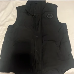 Canada Goose Black Label - Canada Goose Black Label väst (herr modell) storlek L. Endast prövad i butik men kom tyvärr aldrig till användning. Köpt i NK, digitalt kvitto finns. Ny pris 7299:- mitt pris 3500:-  Pris kan diskuteras vid snabb affär. 