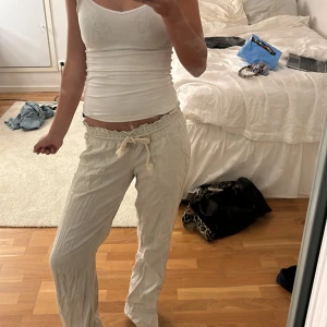 Beige linnebyxor med snörning - Säljer ett par superbekväma beige linnebyxor med elastisk midja och snörning. Perfekta för en avslappnad stil, kanske för en dag på stranden eller bara chilla hemma. De har en loose passform som gör dem extra sköna att bära.