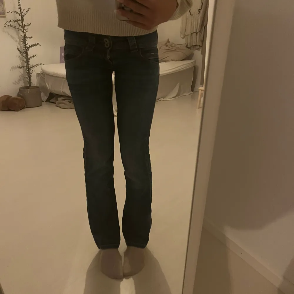 Säljer ett par snygga blå jeans med låg midja och coola detaljer som dubbla knappar fram. Jeansen är i bra skick och är i storlek W25💕säljer pga att dom blivit för korta!                     skriv om ni undrar något eller vil ha fler bilder mm🩷. Jeans & Byxor.