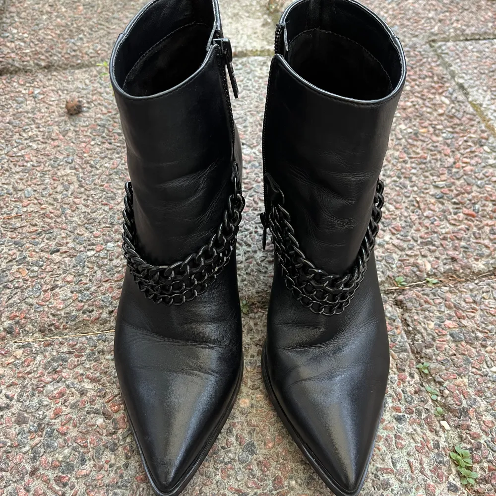 100% genuine leather with a side zipper for easy wear. Set on a 7.5 cm thick heel for comfort. Durable rubber sole and textile inner for added comfort. One circle at the end of the chain is missing on one boot. Slight wear mark (in last picture.) . Skor.