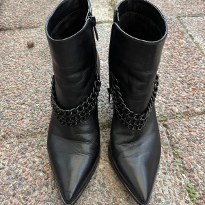 Guess Leather Ankle Boots with Chain Detail - Good Condition - 100% genuine leather with a side zipper for easy wear. Set on a 7.5 cm thick heel for comfort. Durable rubber sole and textile inner for added comfort. One circle at the end of the chain is missing on one boot. Slight wear mark (in last picture.) 
